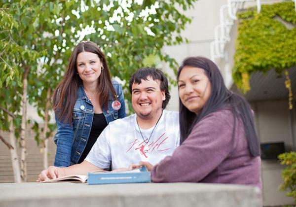 Three students working together at a table outside. 