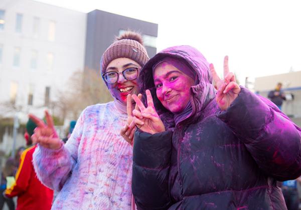 Two happy people covered in pink chalk dust. 